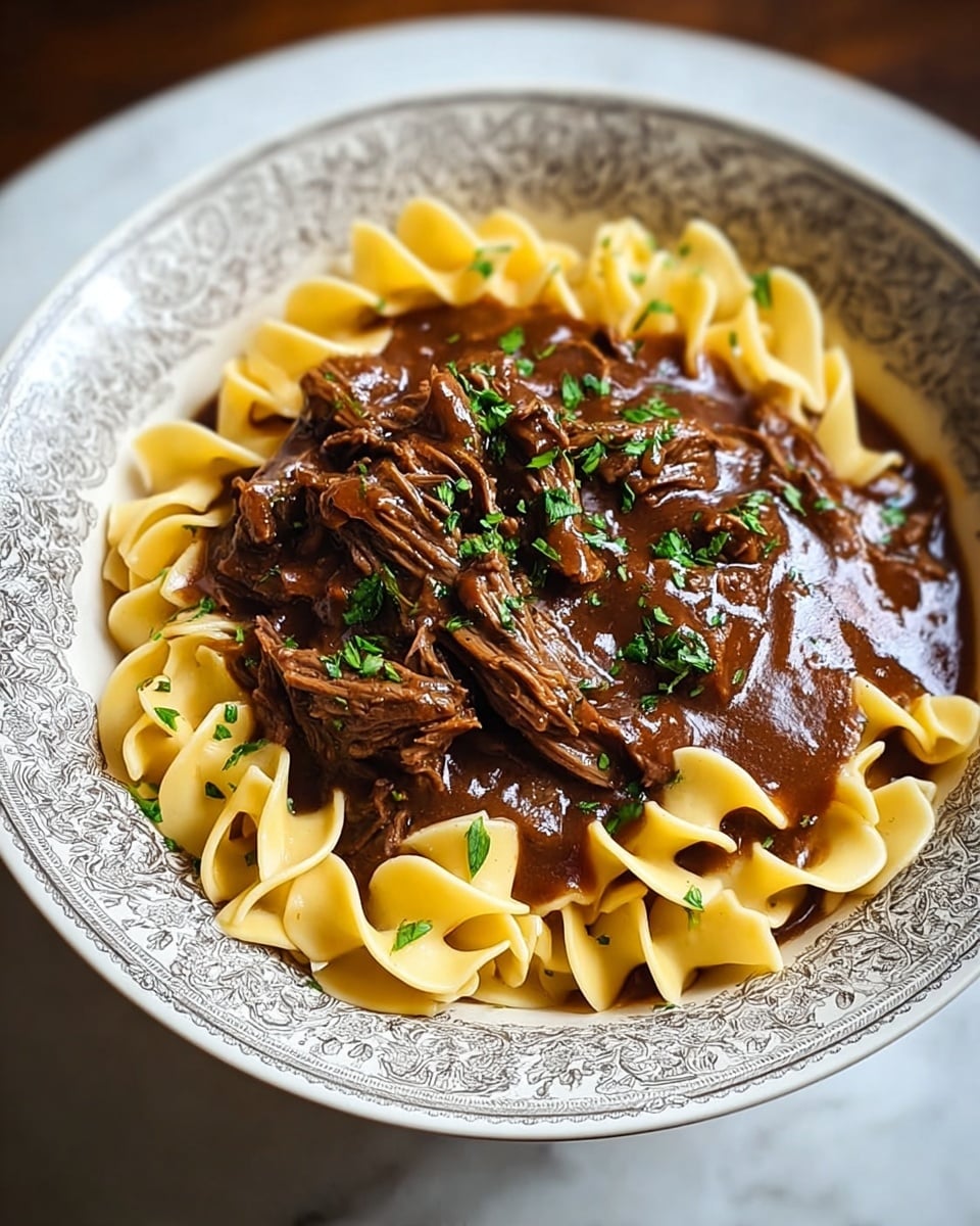 A bowl filled with three layers: the bottom layer shows twisted yellow egg noodles arranged around the edges, soft and slightly curled; the middle layer is thick, dark brown beef stew gravy covering the noodles; the top layer has shredded pieces of beef mixed in the stew, garnished with small specks of fresh green herbs. The bowl is detailed with a grayish intricate floral pattern on the outside and sits on a white marbled surface. photo taken with an iphone --ar 4:5 --v 7