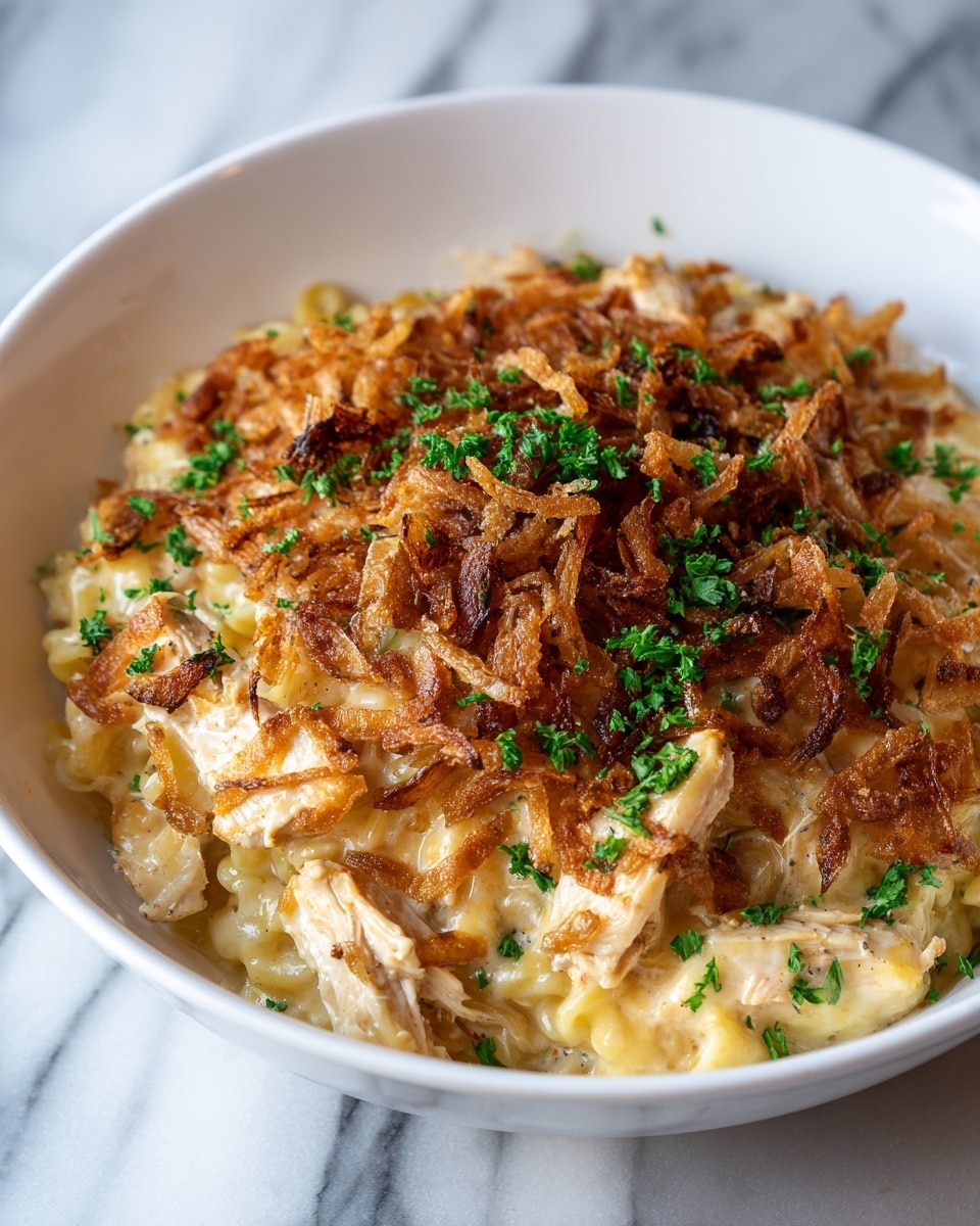 A close-up of a white bowl filled with creamy orzo pasta cooked in a light cheese sauce. The pasta layer is pale yellow with a smooth, slightly shiny texture. On top, there is a generous layer of crispy fried onions that are golden brown with some darker edges for a crunchy look. Small bits of bright green chopped parsley are scattered over the pasta and crispy onions, adding fresh color. The bowl is set on a soft, white marbled surface with a soft cloth underneath. photo taken with an iphone --ar 4:5 --v 7