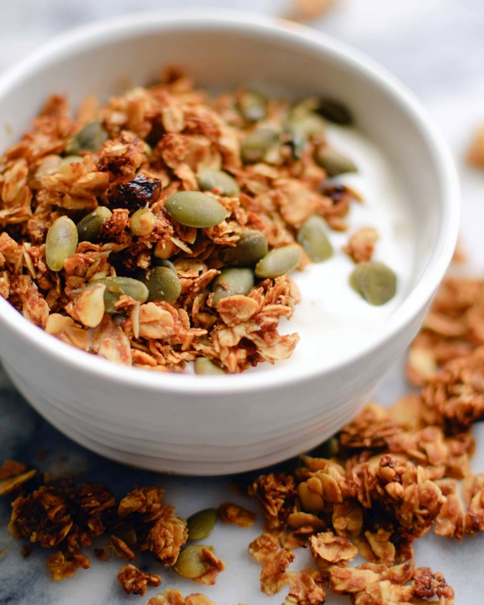 A white bowl filled with creamy white milk at the bottom layer, topped with a thick layer of golden brown granola mixed with green pumpkin seeds scattered evenly on top. Around the bowl are more loose granola clusters on a white marbled surface, adding texture and depth to the scene. The granola looks crunchy with visible oats and seeds of varied shapes and sizes. photo taken with an iphone --ar 4:5 --v 7
