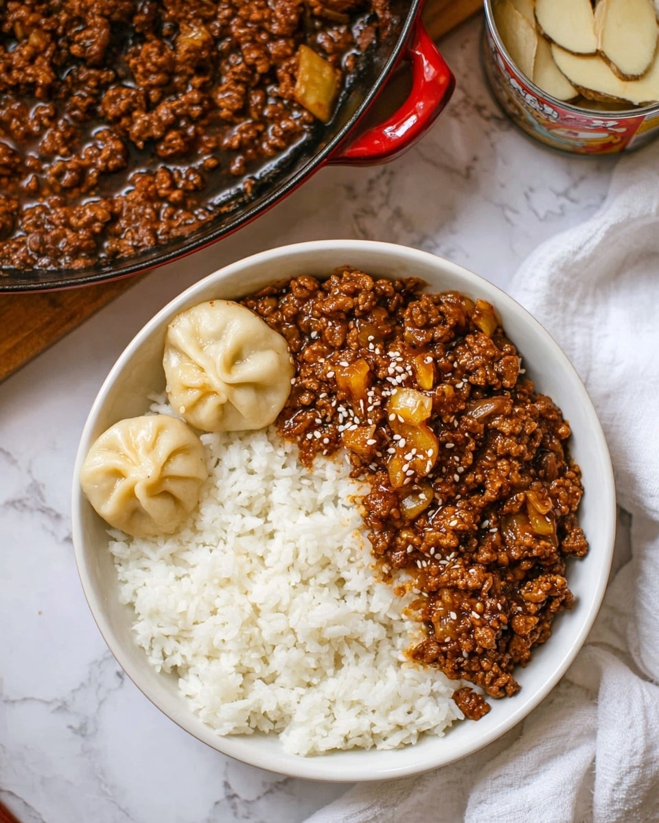 A white round bowl contains three main parts: on the right side, there is a layer of fluffy white rice with visible individual grains; to the left of the rice, there is a serving of minced meat coated in a glossy, dark brown sauce with some small chunks of light yellow vegetables or fruit mixed in, topped with a few white sesame seeds; at the top left corner of the bowl, two small round dumplings with smooth, pale yellow skins and pleated tops sit next to the rice. The bowl rests on a white marbled surface, with part of a red-handled pan filled with the same minced meat mixture visible in the background, along with an open can containing thick, light-colored slices. A white cloth is folded near the bowl. photo taken with an iphone --ar 4:5 --v 7