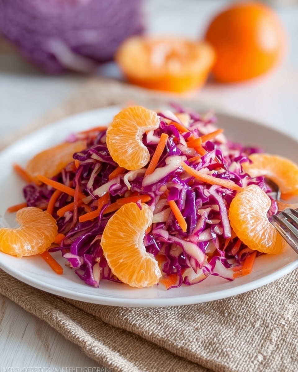 A white plate holds a small mound of salad made of three main layers: shredded purple cabbage forming the base layer with thin, long purple strips mixed with thin orange carrot shreds scattered evenly on top. Bright orange mandarin slices are placed on the outer layer around the salad, providing a fresh, juicy look with a shiny texture. The plate sits on a beige woven cloth and is placed over a white marbled surface with a blurred background showing an orange and some purple cabbage. A silver fork is seen at the bottom right corner. Photo taken with an iphone --ar 4:5 --v 7