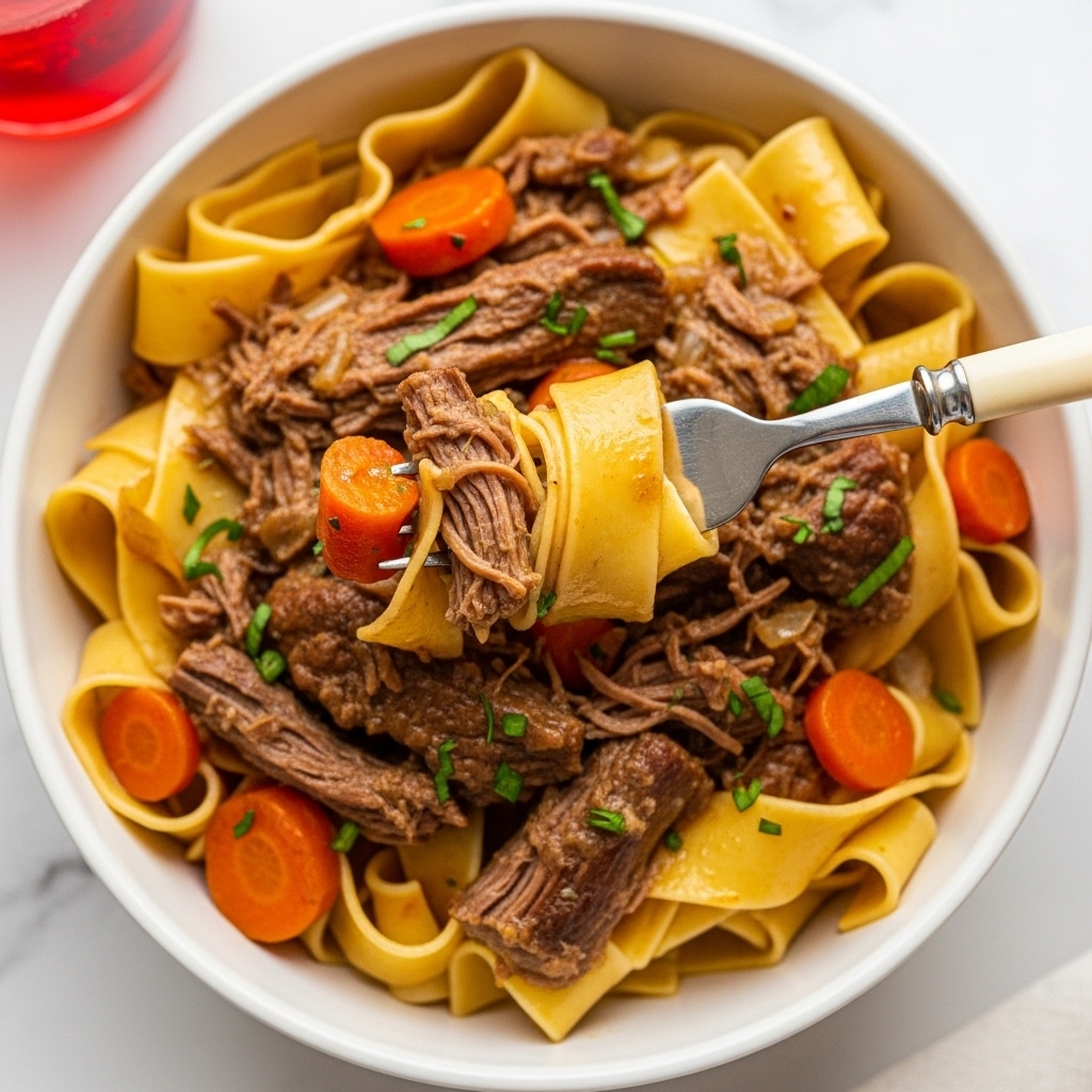 The image shows a white bowl filled with wide, flat pappardelle pasta ribbons, mixed with shredded beef and small chunks of orange carrots, all coated in a rich brown sauce. The beef looks tender and juicy with visible fibers, while the carrots add a pop of bright color. Finely chopped green herbs are sprinkled on top, adding a fresh touch. A fork with a creamy handle is lifting a bite that holds pasta, beef, and carrot pieces together. The bowl sits on a white marbled surface, and part of a red drink in a glass is visible at the top left corner. photo taken with an iphone --ar 4:5 --v 7